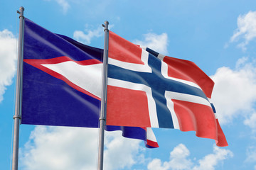 Norway and American Samoa flags waving in the wind against white cloudy blue sky together. Diplomacy concept, international relations.