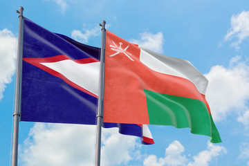 Oman and American Samoa flags waving in the wind against white cloudy blue sky together. Diplomacy...