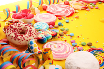 sweet carnival donuts with streamer and confetti on yellow background