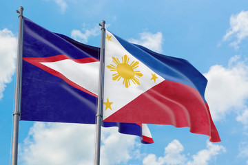 Philippines and American Samoa flags waving in the wind against white cloudy blue sky together. Diplomacy concept, international relations.