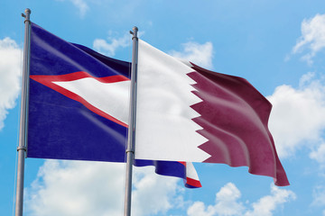 Qatar and American Samoa flags waving in the wind against white cloudy blue sky together. Diplomacy concept, international relations.