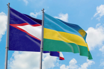 Rwanda and American Samoa flags waving in the wind against white cloudy blue sky together. Diplomacy concept, international relations.