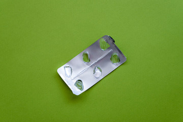 Empty pill blister pack on a green background.