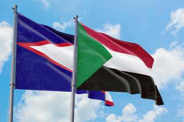 Sudan and American Samoa flags waving in the wind against white cloudy blue sky together. Diplomacy concept, international relations.