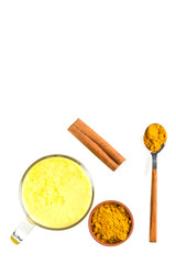 Top view of a cup of golden milk with turmeric and cinnamon and wooden spoon isolated on white background