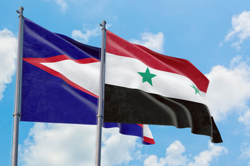 Syria and American Samoa flags waving in the wind against white cloudy blue sky together. Diplomacy...