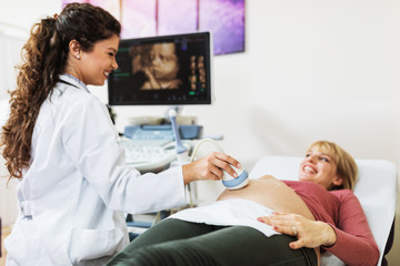 Obstetrician examining pregnant belly by ultrasonic scan.