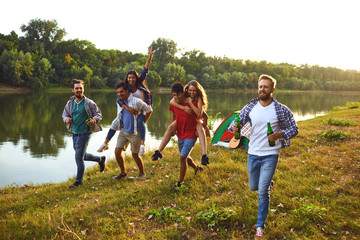 Friends have fun running along the lake on a picnic.