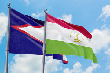 Tajikistan and American Samoa flags waving in the wind against white cloudy blue sky together. Diplomacy concept, international relations.