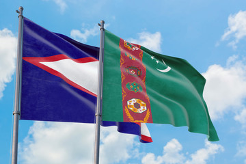 Turkmenistan and American Samoa flags waving in the wind against white cloudy blue sky together....