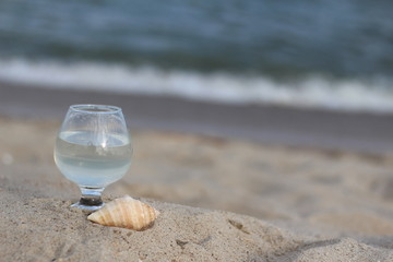 A glass on a background of blue water and the sea on a summer day