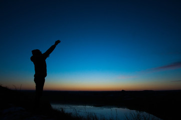 Pray. Silhouetted men on a background of blue sky and sunset. With arms raised. Prayer to God....