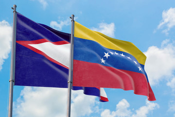 Venezuela and American Samoa flags waving in the wind against white cloudy blue sky together. Diplomacy concept, international relations.