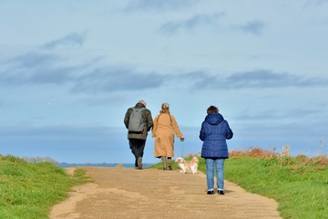 family who is walking on the path of the pink granite coast at Tregastel in Brittany. France