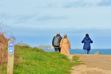 family who is walking on the path of the pink granite coast at Tregastel in Brittany. France