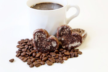 Cup of coffee and gingerbreads in heart shape with coffee beans on white background, Valentines day romantic breakfast. Concept of sweet love, morning dessert