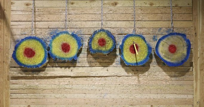 Bullseye target Axe wooden slow motion. Sport and competition where a sharp axe and other metal weapons are thrown at a bulls eye wooden target for fun and score. Family friend recreation.