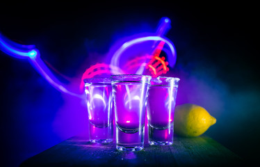 Club drink concept. Tasty alcohol drink cocktail tequila with lime and salt on vibrant dark...