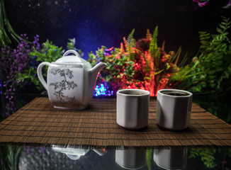 Obraz na płótnie Canvas Tea concept. Japanese tea ceremony culture east beverage. Teapot and cups on table with bamboo leaves on sunset