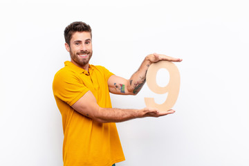young handsome man excited, happy, joyful, holding a number 9.