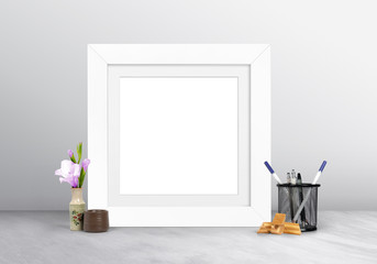 White blank empty photo frame along pen holder and flower pot