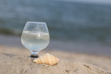 A glass on a background of blue water and the sea on a summer day