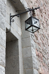 A hinged wrought-iron and glass lantern hangs over the entrance to the medieval fortress