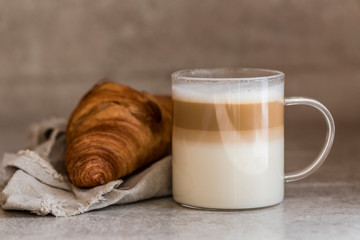 A cup of coffee latte macchiato with a croissant