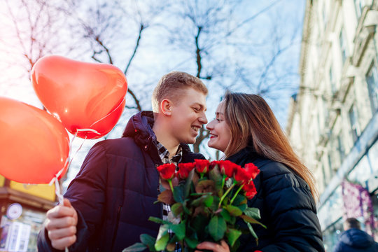 Valentines Day Date. Man And Woman About To Kiss Outdoors. Couple Walking With Roses Flowers And Balloons