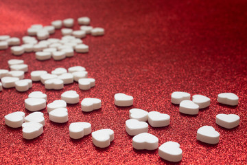 Many white sweet candys or pills on the red background, copyspace.