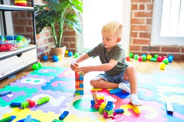 Young caucasian kid playing at kindergarten with toys. Preschooler boy happy at playroom.