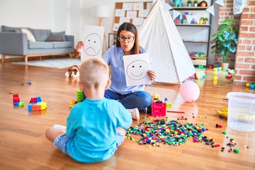 Young therapist woman speaking with child, counselor and behaviour correction at the office showing happy and sad face
