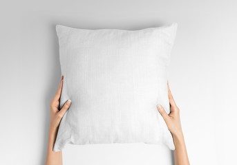 White blank square pillow mockup, woman holding with two hands on isolated background
