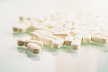 White medicines on table glass surface with reflection and light. Medication and dietary supplements concept.