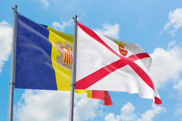 Jersey and Andorra flags waving in the wind against white cloudy blue sky together. Diplomacy concept, international relations.