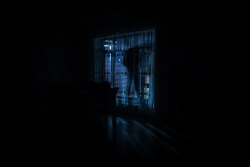 Silhouette of a man standing at a window inside the room. Fantasy picture with old vintage lantern...