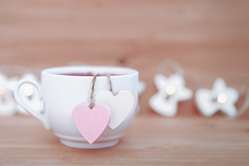 Heart shaped tea bag in white cup of tea - cute love declaration on wooden background