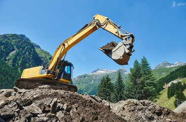 excavator loader machine at construction earthmoving work in mountains
