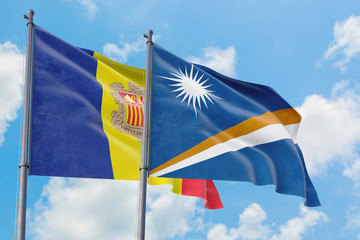 Marshall Islands and Andorra flags waving in the wind against white cloudy blue sky together. Diplomacy concept, international relations.