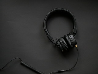 Modern black headphones on color background