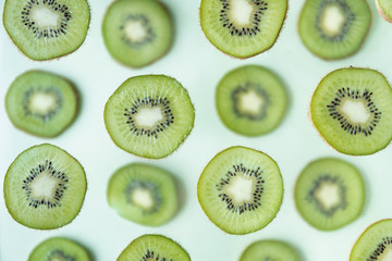 Fototapeta premium Pattern of kiwi slices levitating above green background