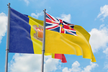 Niue and Andorra flags waving in the wind against white cloudy blue sky together. Diplomacy concept, international relations.