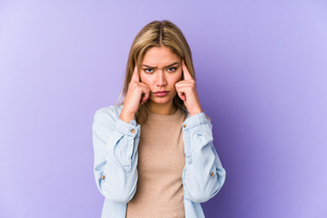 Young blonde caucasian woman isolated focused on a task, keeping forefingers pointing head.