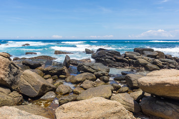 Fototapeta na wymiar A powerful wave with splashes and foam breaks on a rocky shore. Sri Lanka