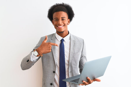 Young african american businessman using laptop standing over isolated white background with surprise face pointing finger to himself