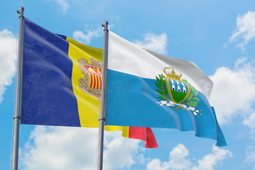 San Marino and Andorra flags waving in the wind against white cloudy blue sky together. Diplomacy concept, international relations.