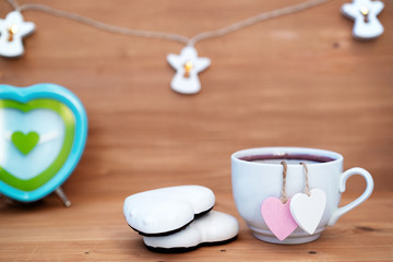 Heart shaped tea bag in white cup of tea - cute love declaration on wooden background, selective focus. Valentines day concept. Mug of tea for two lovers honeymoon wedding morning surprise breakfast