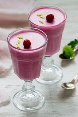 Berry-fruit mousse decorated with raspberries on a light background.