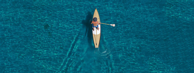 Aerial drone ultra wide top down photo of male Stand Up Paddle board surfer paddling in tropical...
