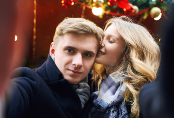 elegant romantic couple in love making selfie, kissing and posing on festive decorations background.